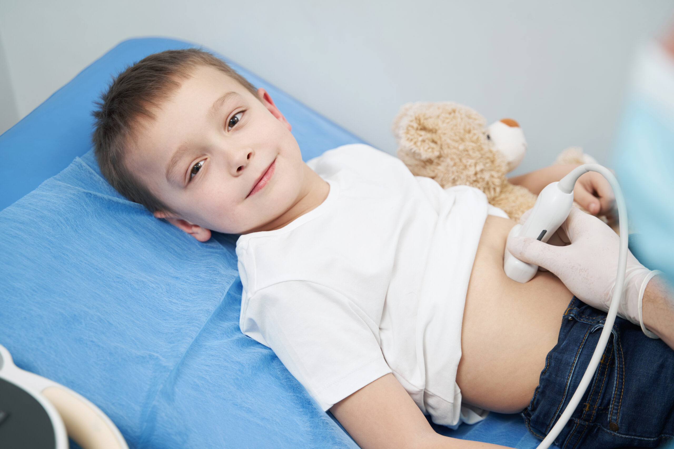 Smiling young boy lying on couch in clinic undergoing an abdominal ultrasound